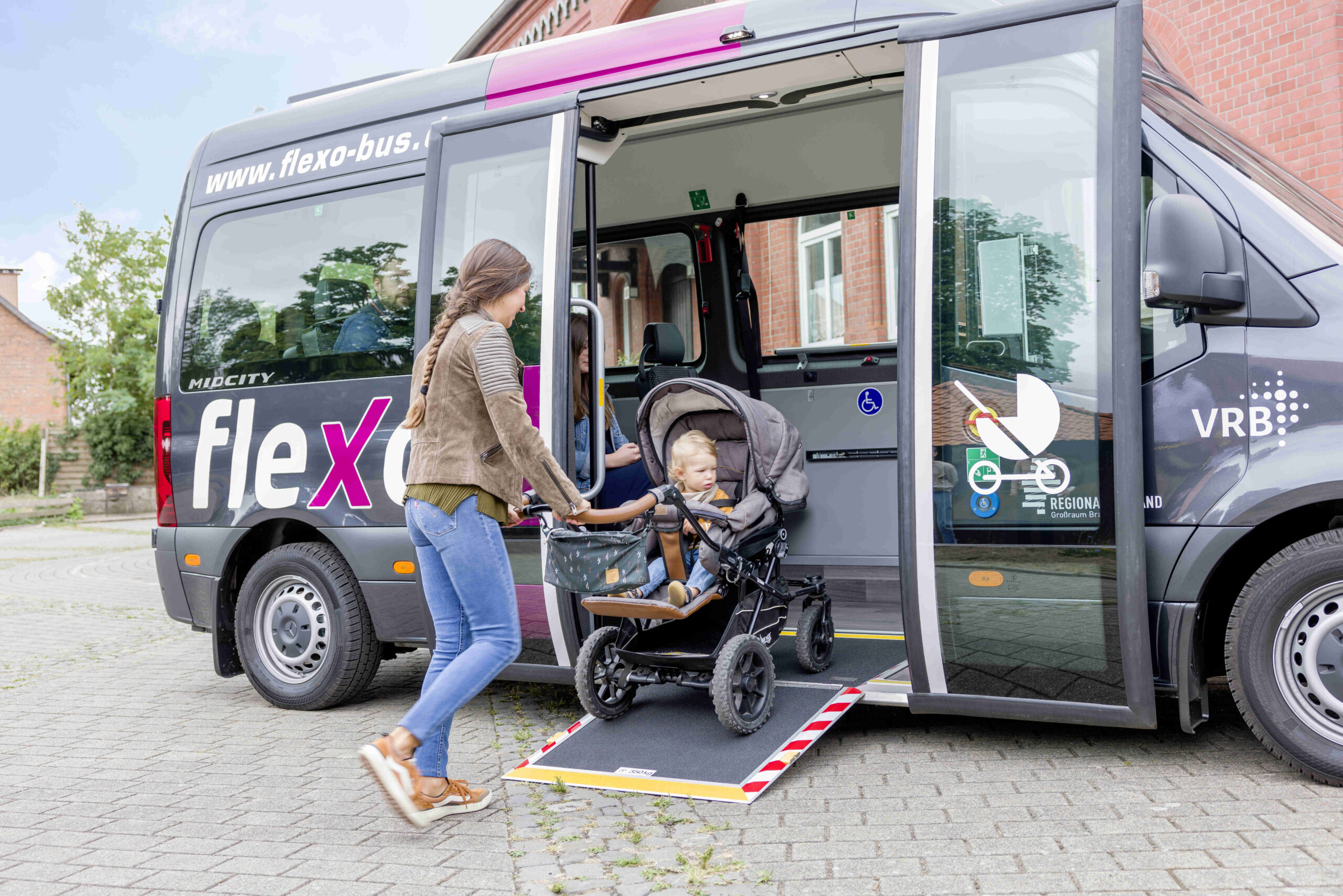Frau steigt mit Kinderwagen in den flexo Bus ein